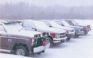 Snow-covered pickup trucks parked in severe winter conditions